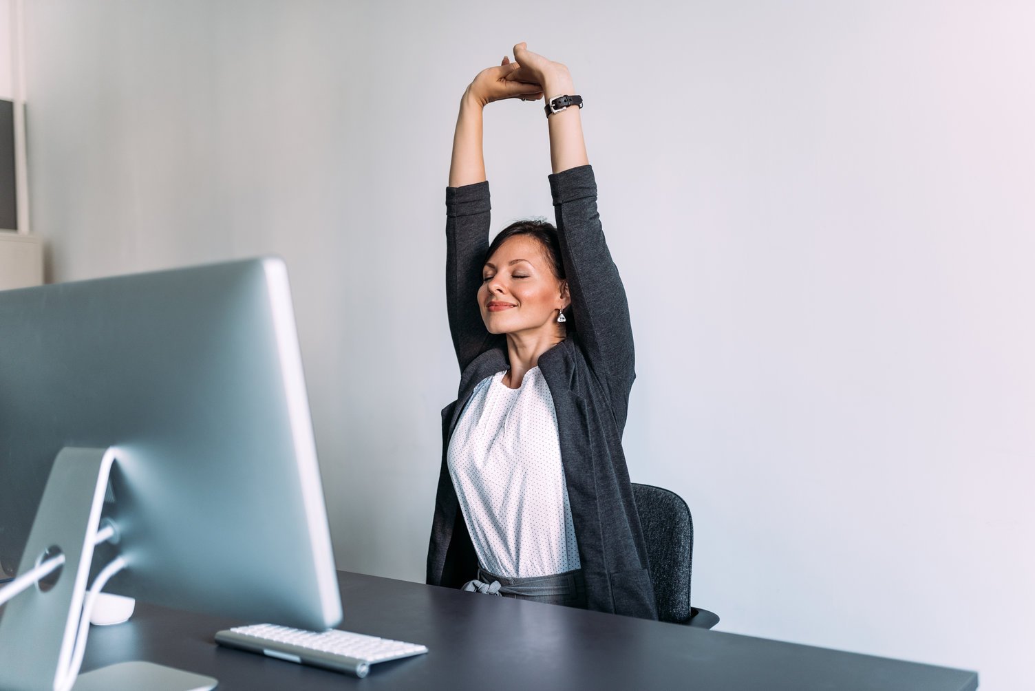 woman stretching at work to relieve stress and tension from shoulders and back